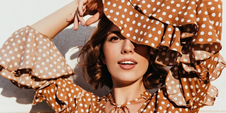 Veja como arrasar com poá na primavera com essas dicas de estilo 1 Modelo feminina usando vestido de poá marrom com detalhes modernos, exibindo estilo elegante na primavera.