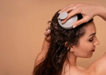Scalp Care: A nova tendência de beleza que está mudando a forma de cuidar dos cabelos 12 Mulher aplicando escova de massagem no couro cabeludo para cuidados capilares.