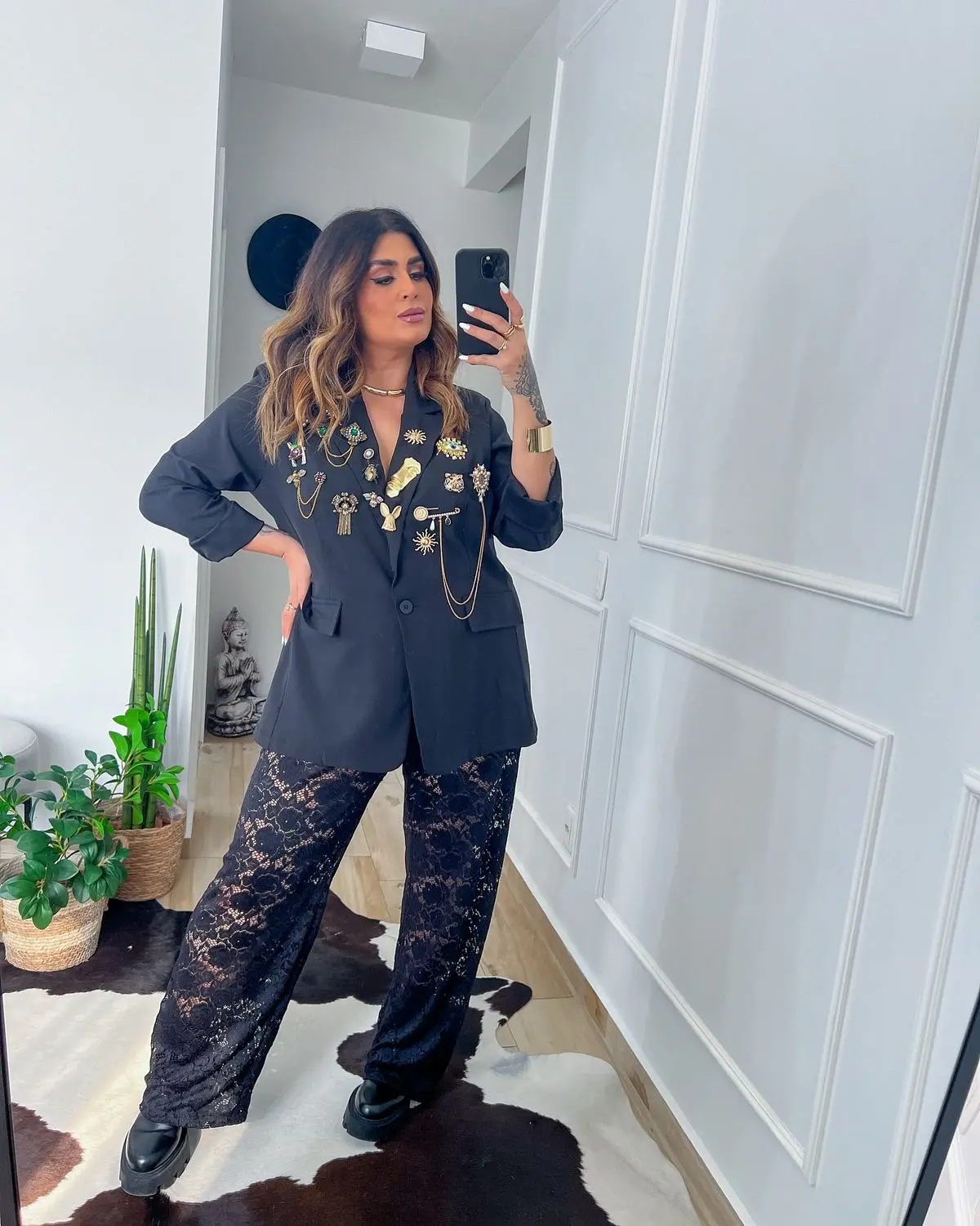 Look moderno com calça de renda e blazer decorado com broches, destacando o truque das sobreposições inteligentes.
