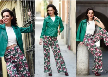 Mulher usando uma calça estampada florida e jaqueta verde em cenário urbano na primavera de 2025, destacando um look moderno e elegante.