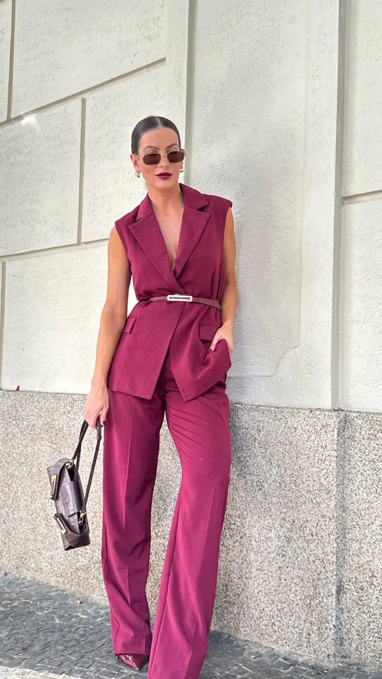 Mulher usando um colete de alfaiataria vinho com calça de alfaiataria combinando, criando um look sofisticado e moderno.