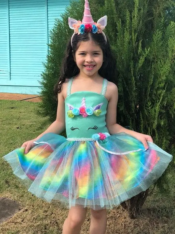 Criança usando fantasia de unicórnio com saia de tule colorida e tiara de unicórnio