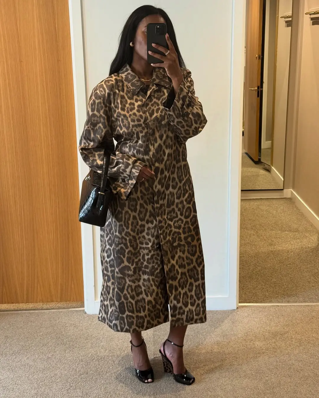Mulher usando vestido animal print e anabela preta com salto, refletida em espelho.