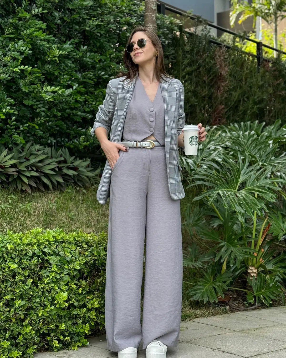 Mulher usando um look monocromático com calça e colete da mesma cor, criando uma linha contínua que alonga a silhueta.