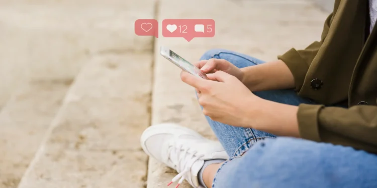 Mulher interagindo com o celular, acompanhada de curtidas e comentários nas redes sociais, simbolizando a conexão digital em outubro.