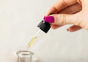 Conta-gotas com óleo de semente de uva sendo aplicado para hidratação da pele e dos cabelos.