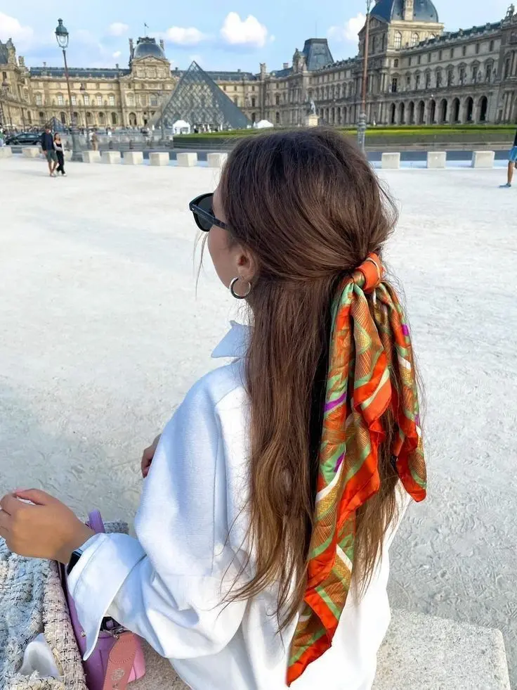 Mulher com lenço colorido amarrado em rabo de cavalo duplo, em frente ao Louvre, Paris.