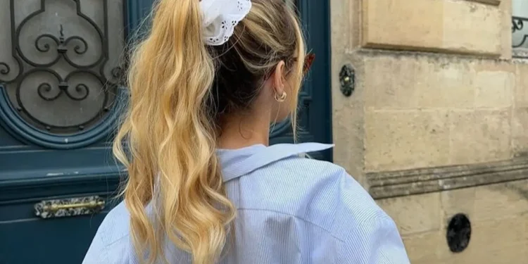 Penteado prático para dias quentes, com cabelo preso em um rabo de cavalo alto e preso por um scrunchie branco.