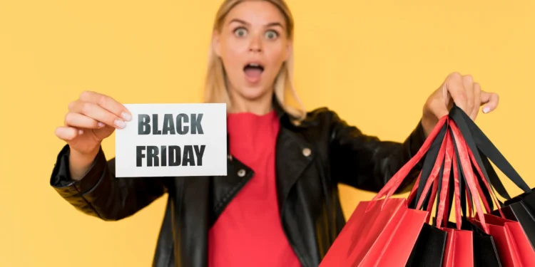 Mulher surpresa segurando sacolas de compras com cartaz escrito Black Friday — moda e beleza em destaque.