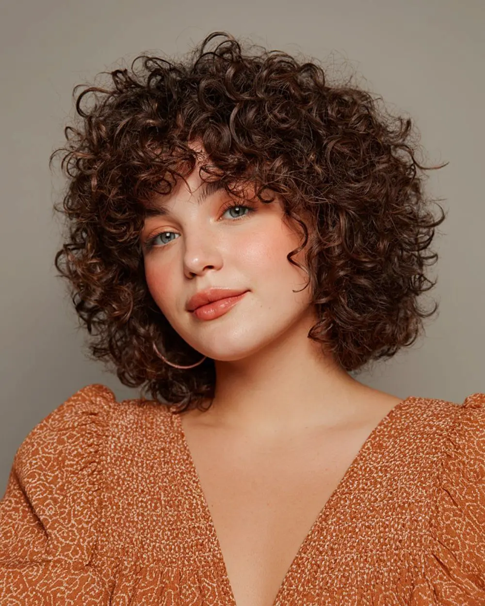 Mulher com cabelo cacheado e corte Halo, com camadas suaves e acabamento arredondado que emoldura o rosto, valorizando a textura natural.