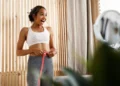 Mulher feliz medindo a cintura após alcançar progresso no treino para o verão.