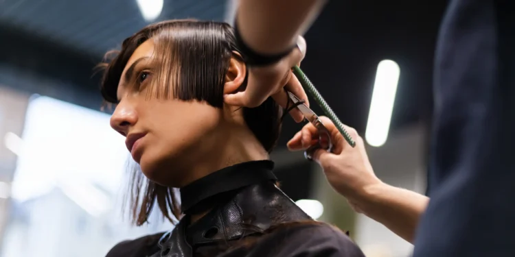 Pessoa recebendo um corte de cabelo moderno com a parte de trás sendo aparada por um cabeleireiro.