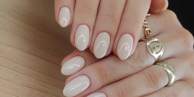 Unhas discretas e sofisticadas: 3 opções que combinam com tudo 1 Unhas curtas com esmalte nude e acabamento brilhante, com anéis dourados delicados, ideal para um visual discreto e sofisticado.