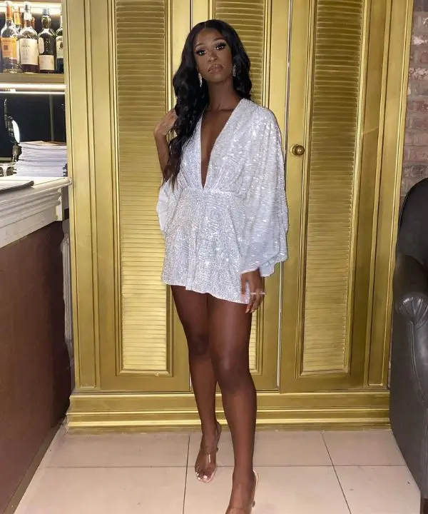 Mulher usando vestido curto com brilho em paetê, estilo perfeito para festas de fim de ano.